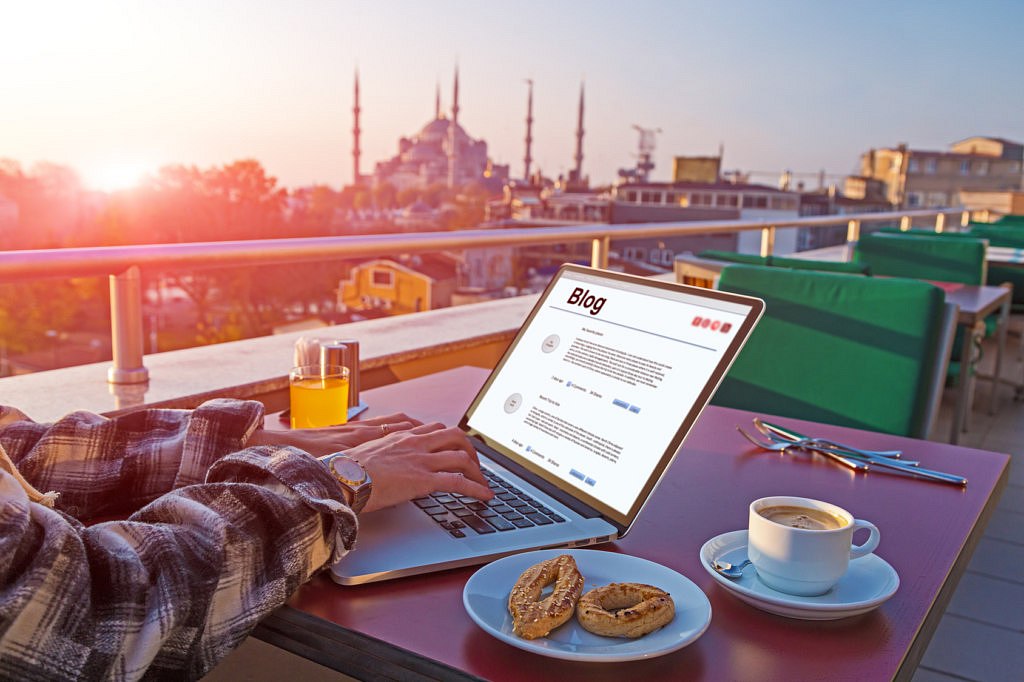 Travelling Person working on Laptop Computer at Roof Top Cafe sitting at table with Coffee Cookies and orange Juice Istanbul city Landscape on background Morning Sunlight